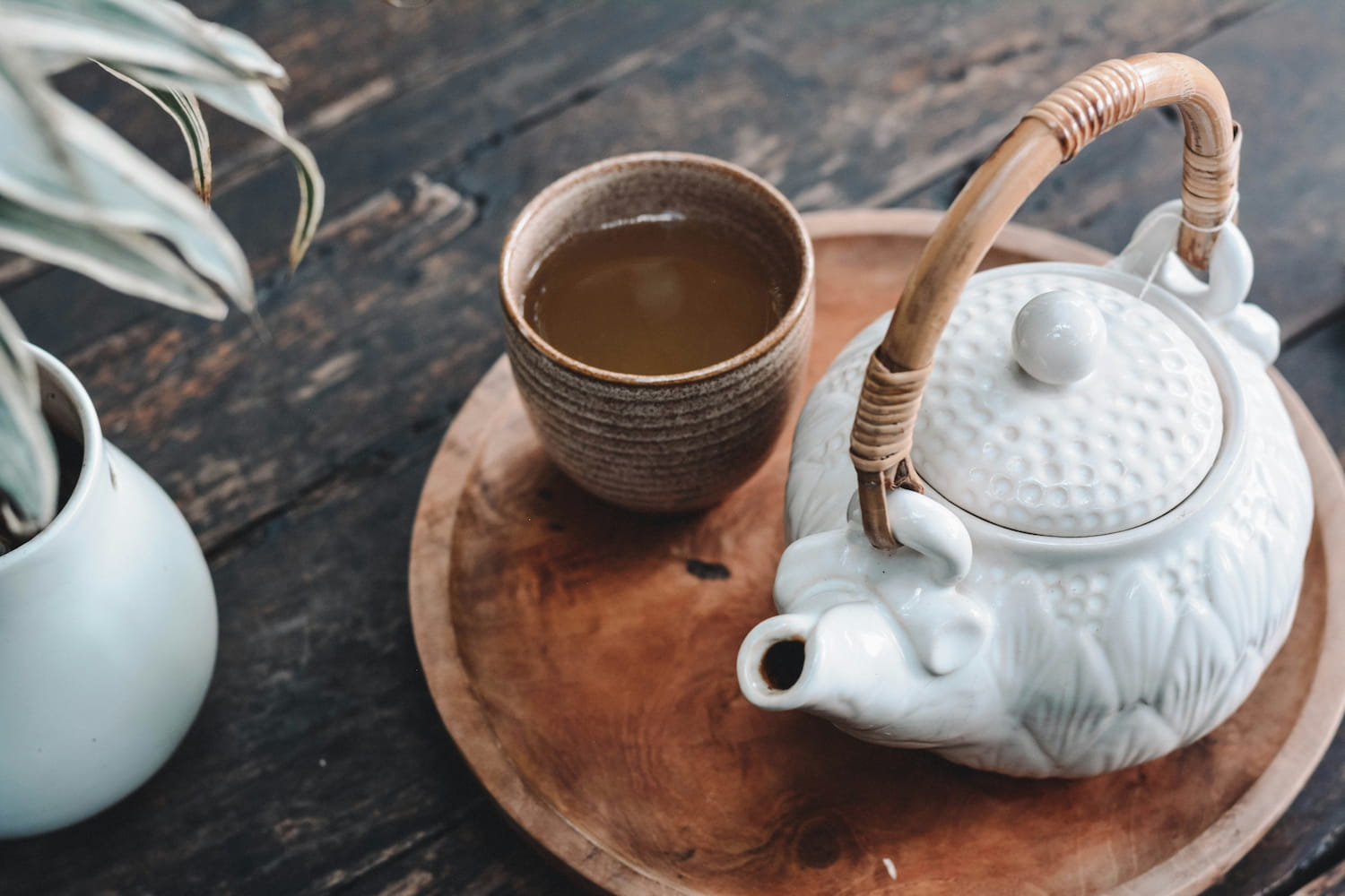 Benefits of Tea Shown Through a Calming Teapot and Cup Setting A ceramic teapot and a warm cup of tea on a wooden tray, visually reflecting the calming benefits of tea